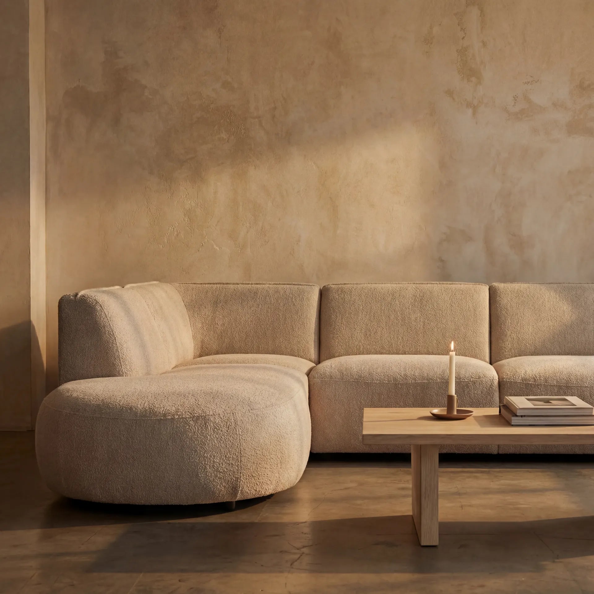Loures Open-End Sectional — warm plaster wall with coffee table, candle and art book