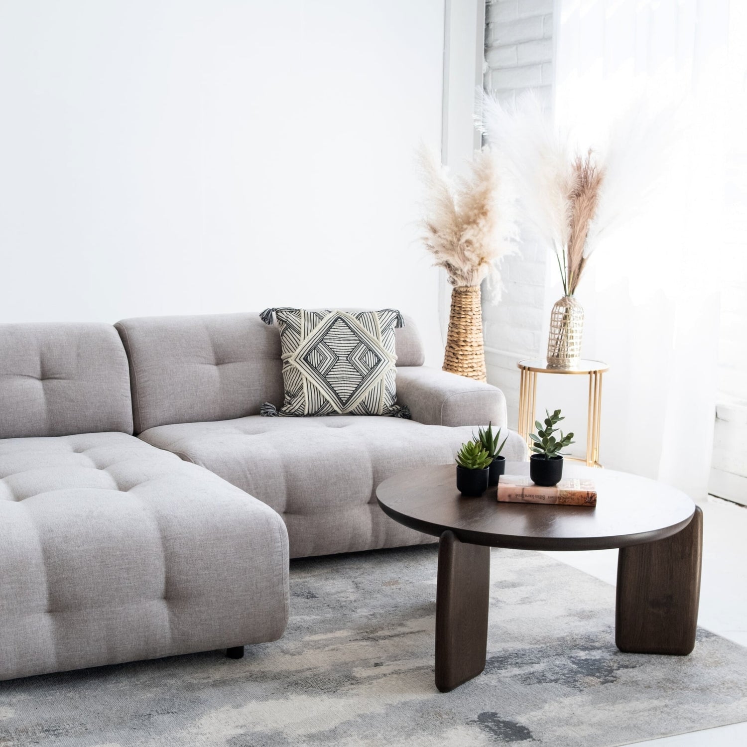 Modern living room with a gray sectional sofa, decorative pillow, and a wooden coffee table.